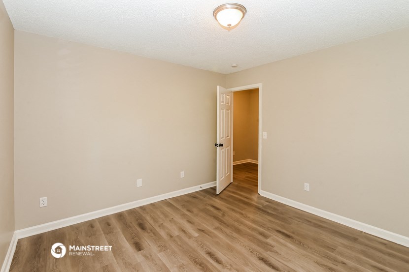 the spacious living room with hardwood flooring and a door to the hallway