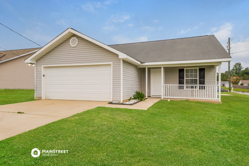 a beige house with a porch and a lawn