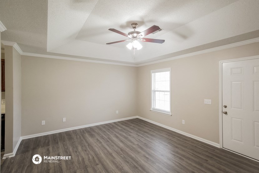 the spacious living room with ceiling fan and wood flooring