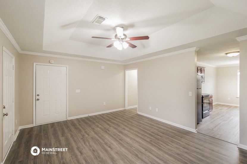 an empty living room with a ceiling fan