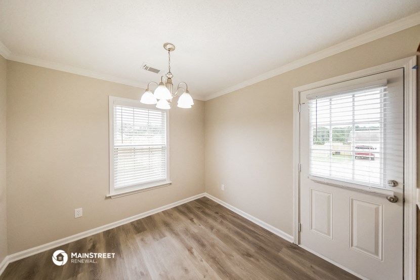 the spacious living room of a house with a white door and window