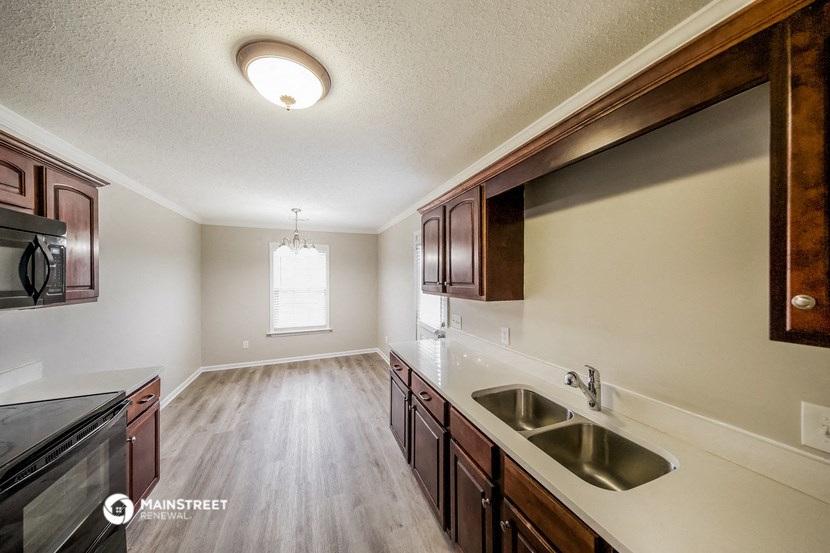an empty kitchen with wood flooring and a large window