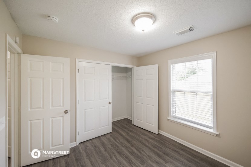 the living room of an apartment with two doors and a window