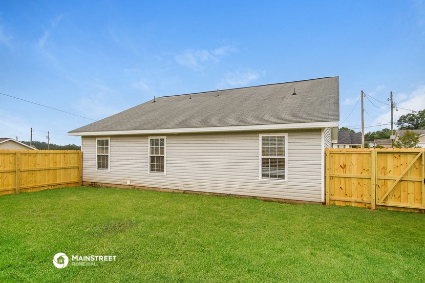 a backyard with a white house and a wooden fence