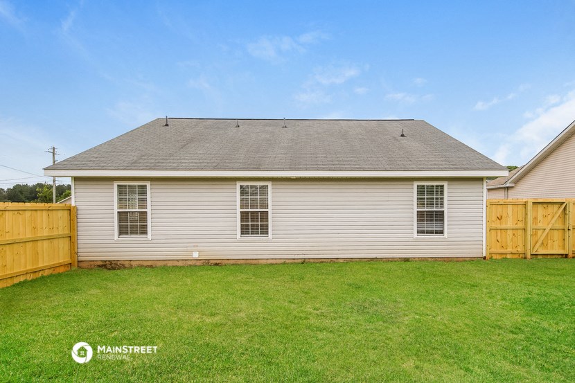 a backyard with a white house and a wooden fence