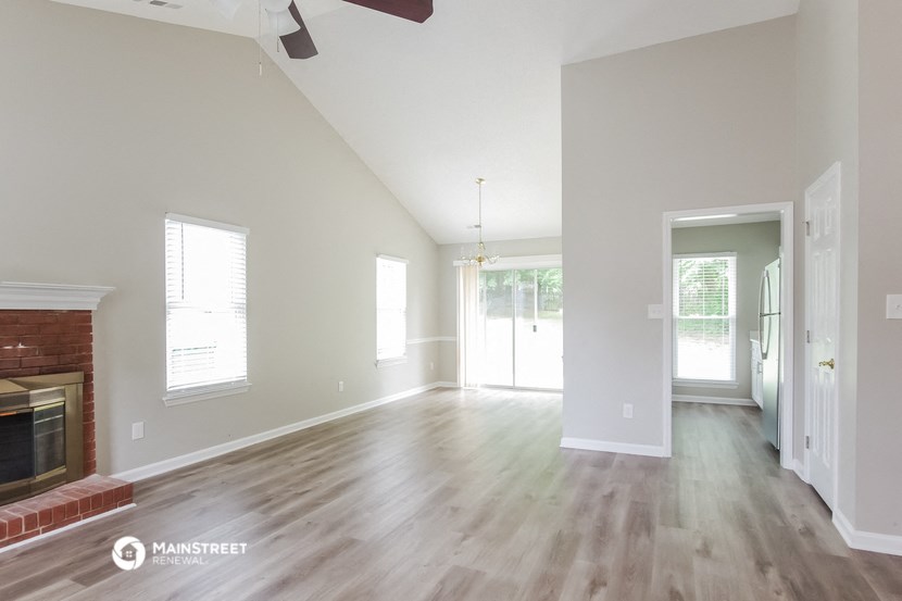 an empty living room with a fireplace and wooden floors