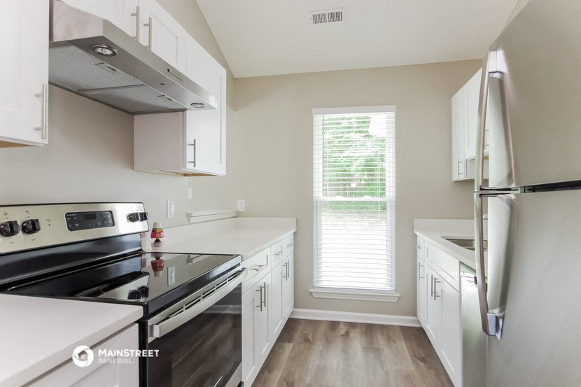 a kitchen with white cabinets and stainless steel appliances and a window