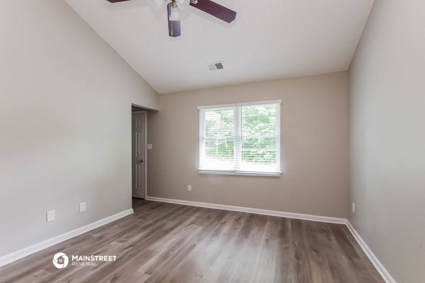 the spacious living room with wood flooring and a ceiling fan