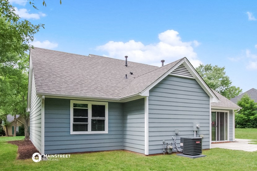 the front of a blue house with a yard and a grill