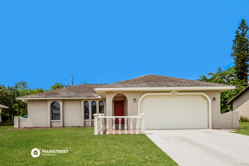 a beige house with a porch and a white fence