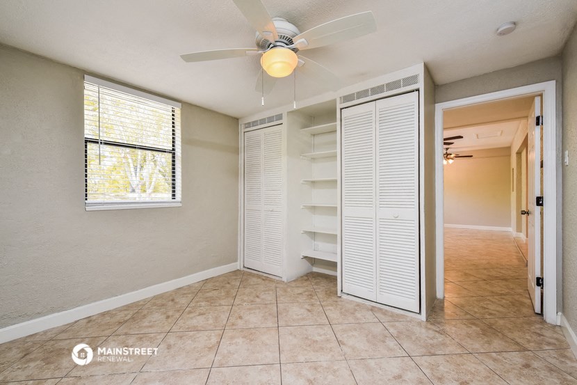 an empty room with a ceiling fan and a closet
