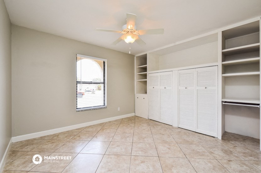 an empty living room with shelves and a ceiling fan