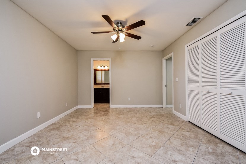 the spacious living room has a ceiling fan and tile flooring