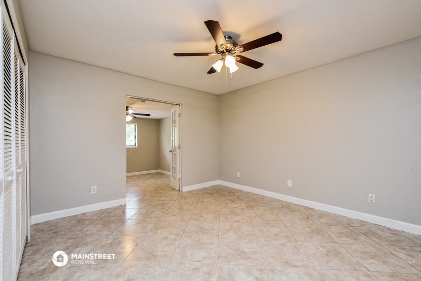 the spacious living room with ceiling fan and tile flooring