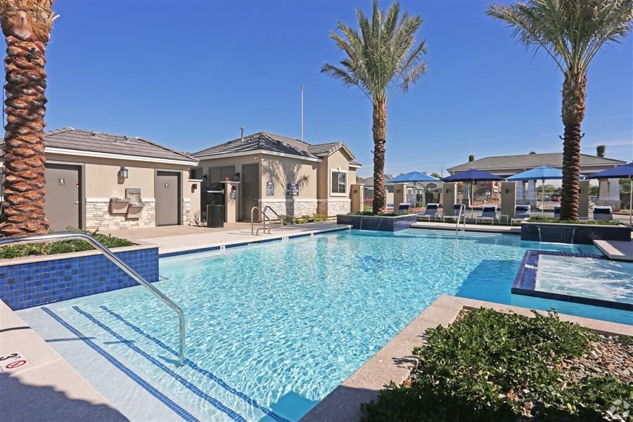 a large swimming pool with palm trees and houses in the background