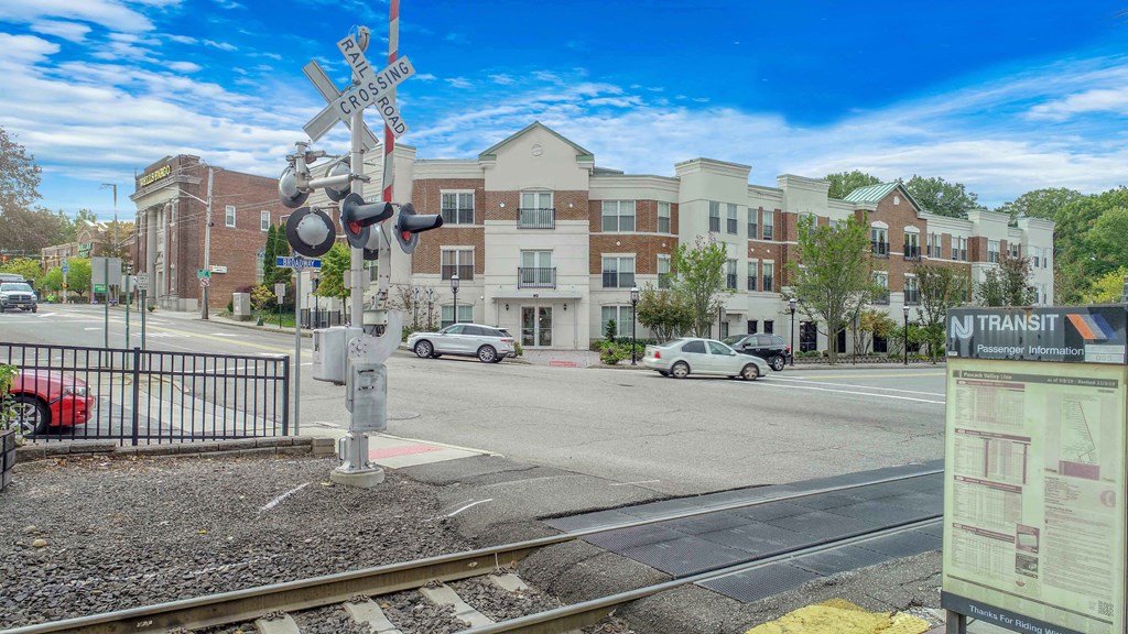 a train crossing at an intersection in front of an apartment building