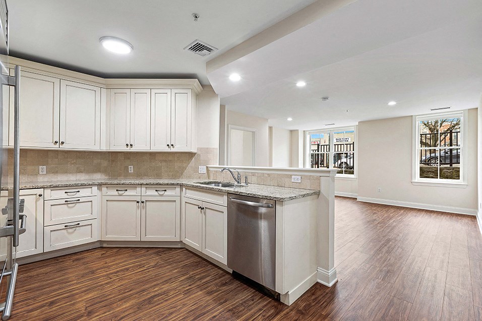 a large kitchen with white cabinets and a stainless steel sink