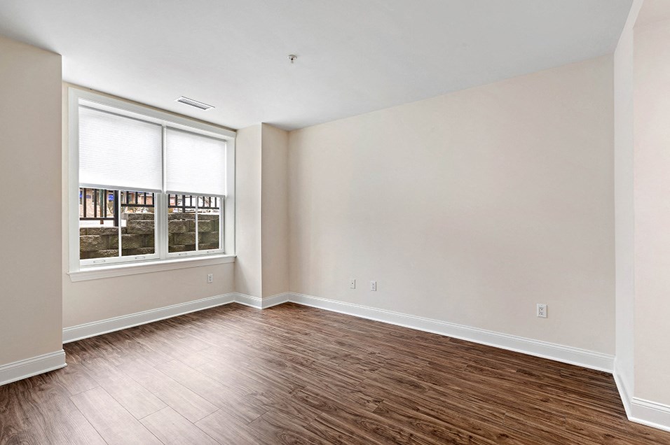 an empty living room with wood floors and a window