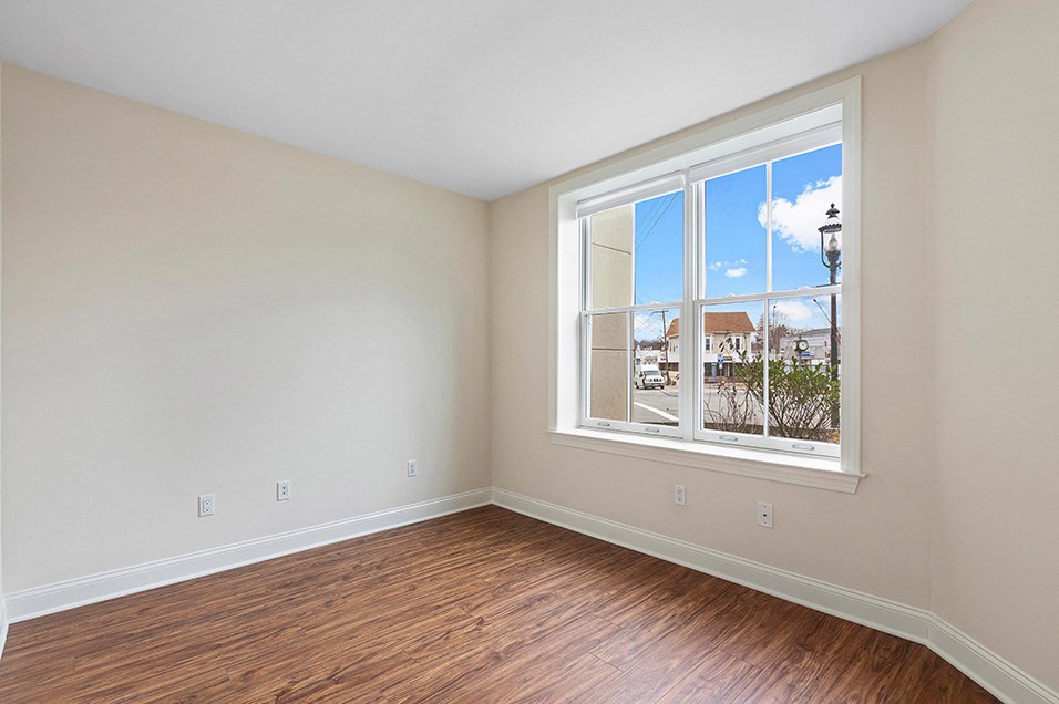 an empty living room with a large window and wooden floors