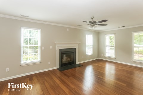 A spacious living room with a fireplace and a ceiling fan.