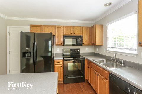 A kitchen with a refrigerator, microwave, oven, and sink.