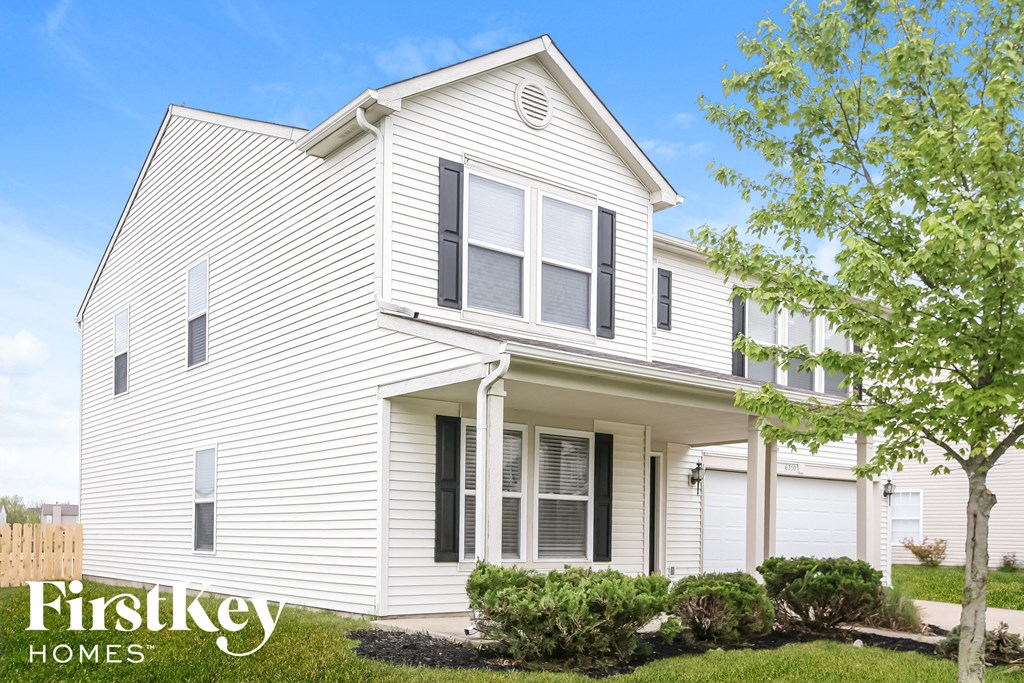a white house with white siding and a lawn and trees