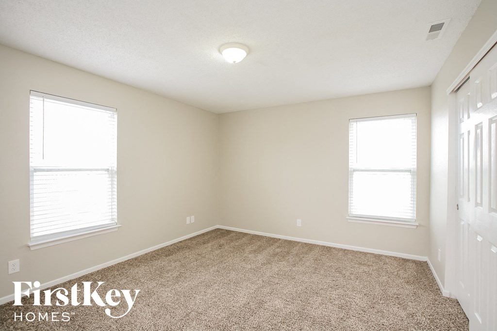 a bedroom with a carpeted floor and two windows