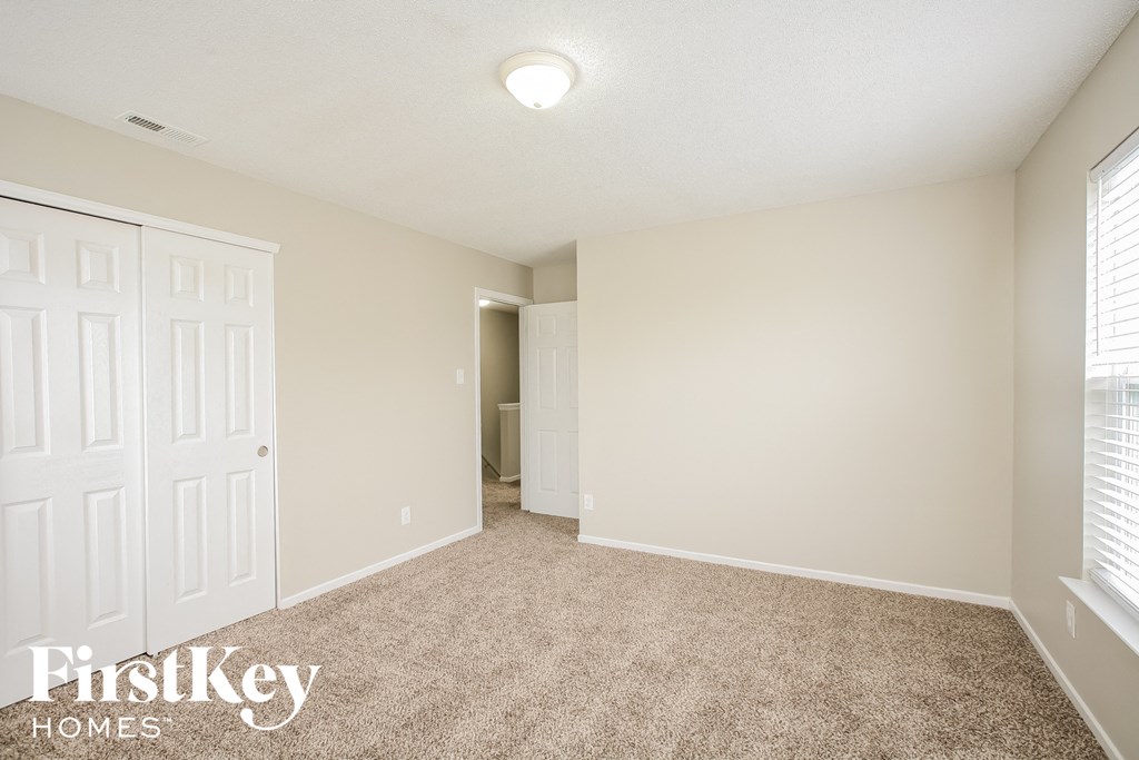 a spacious living room with carpet and a door to a closet