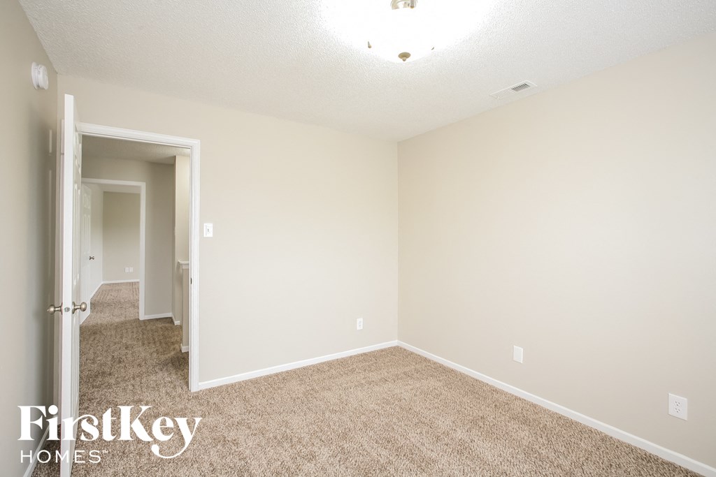 a spacious bedroom with carpeted flooring and white walls