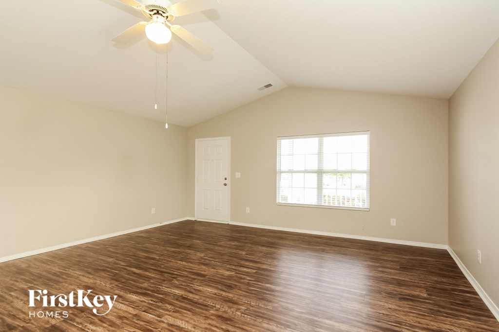 the spacious living room with hardwood flooring and a ceiling fan