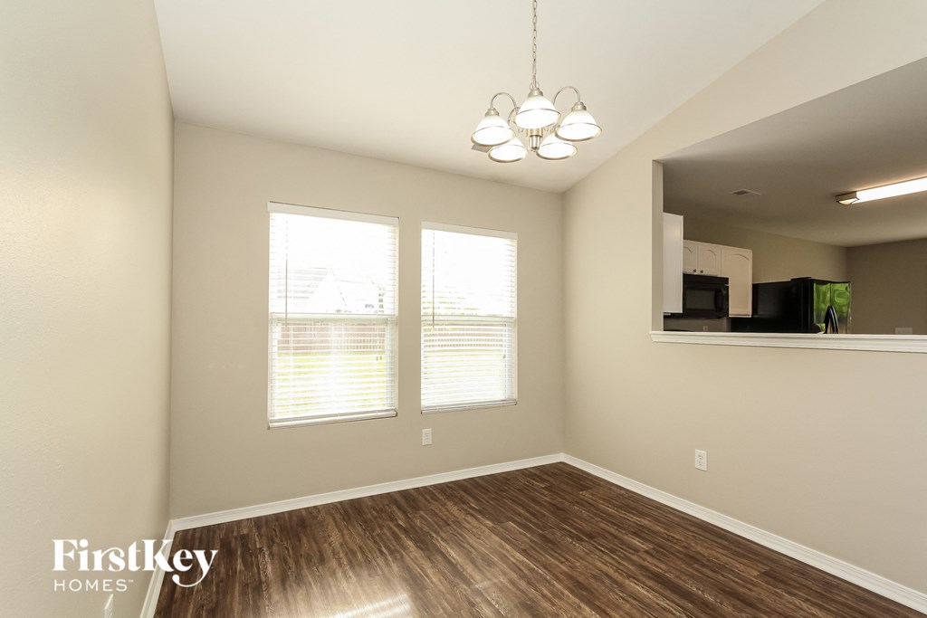 an empty living room with wood flooring and two windows
