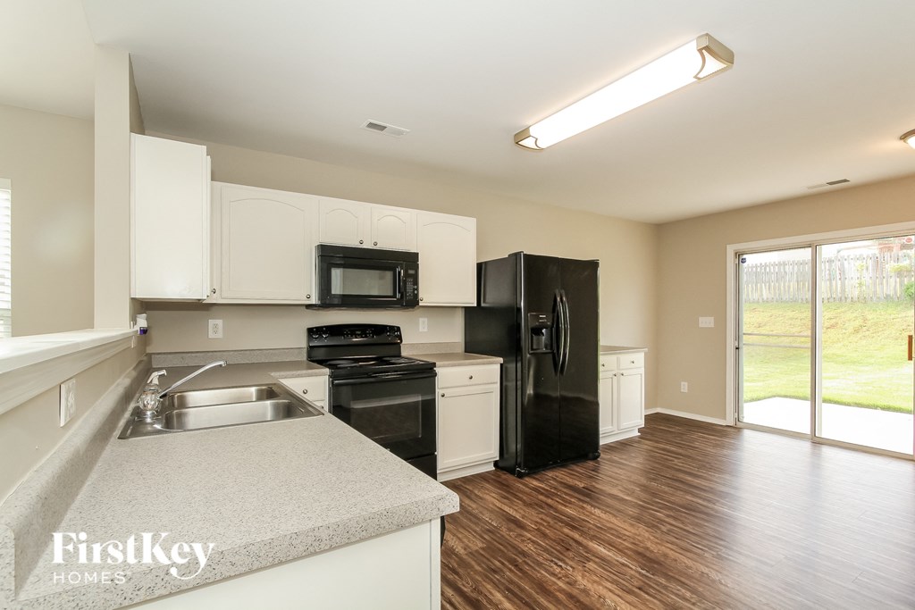 a kitchen with white cabinets and black appliances