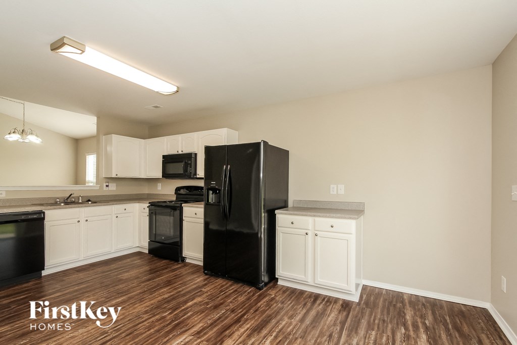 a kitchen with white cabinets and a black refrigerator