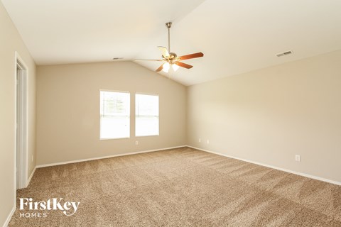 a spacious living room with carpet and a ceiling fan
