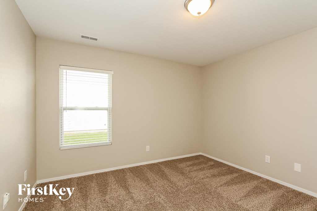 the upstairs bedroom with carpet and a window