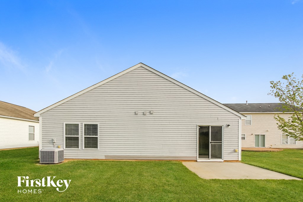 a side view of a white house with a grassy yard