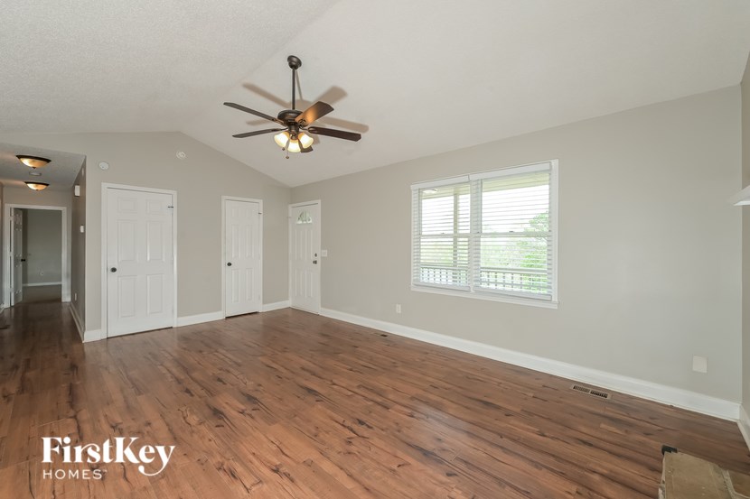 A room with a ceiling fan and wooden floors.