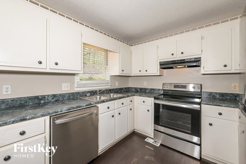 A kitchen with white cabinets and a granite countertop.