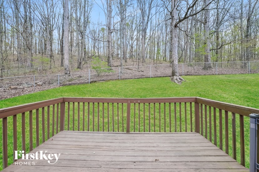 A wooden deck overlooks a grassy area with trees in the background.