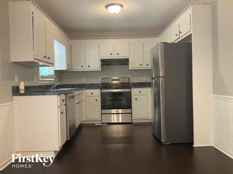 A kitchen with white cabinets and a black refrigerator.
