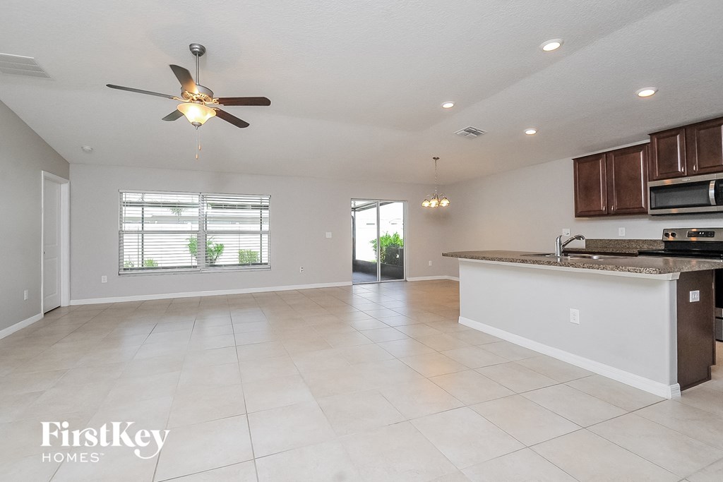 an empty kitchen and living room with a ceiling fan