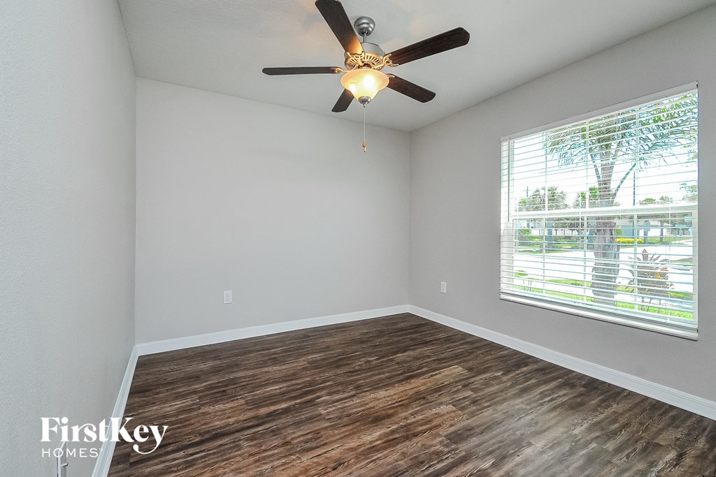 the living room has a large window and a ceiling fan