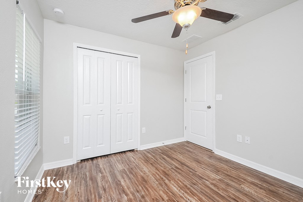 the living room of a home with white walls and a ceiling fan