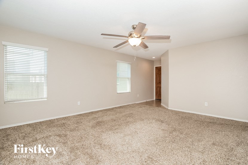 an empty living room with a ceiling fan
