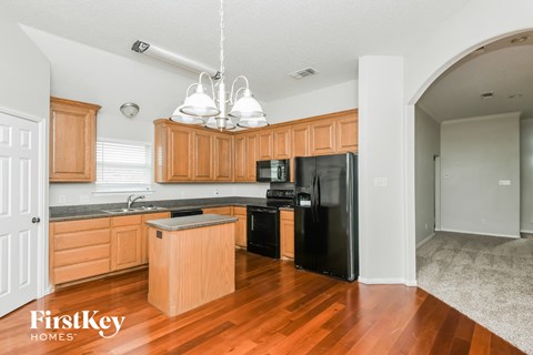 a kitchen with wooden cabinets and a black refrigerator