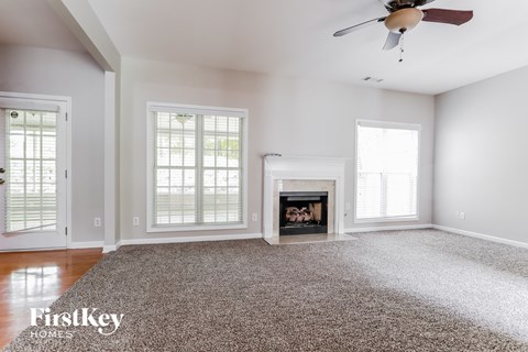 A spacious living room with a fireplace and a rug on the floor.