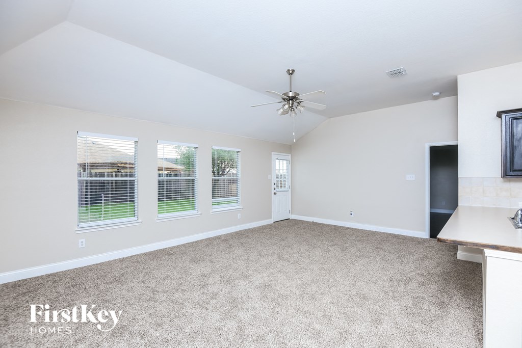 a living room with carpet and a ceiling fan