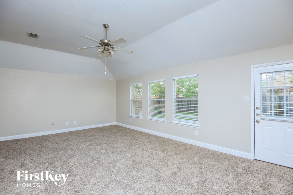 an empty bedroom with a ceiling fan and windows