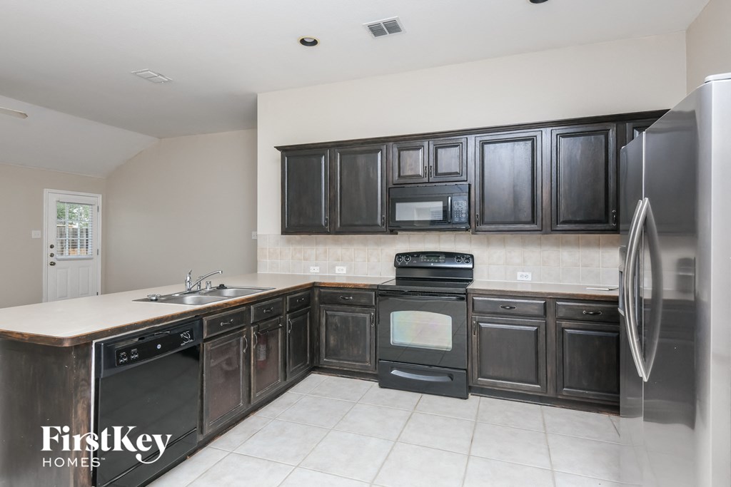 a kitchen with dark wood cabinets and stainless steel appliances