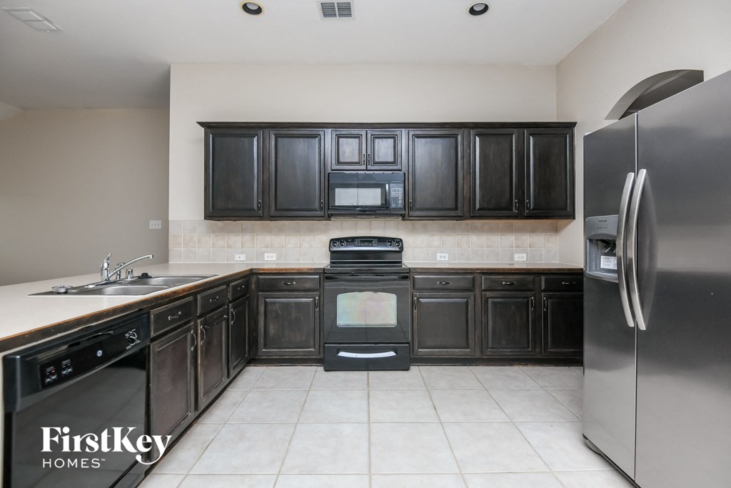 a kitchen with black cabinets and stainless steel appliances